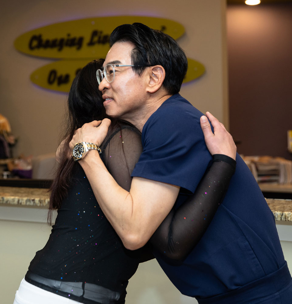 patient and doctor smiling and hugging after patient's dental procedure within the dental center