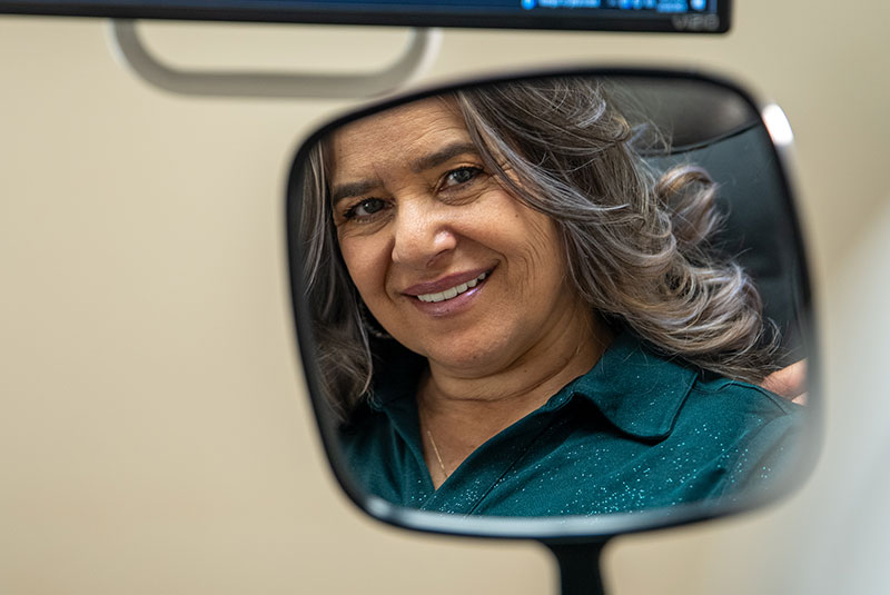 patient smiling brightly while looking at their smiling in the mirror